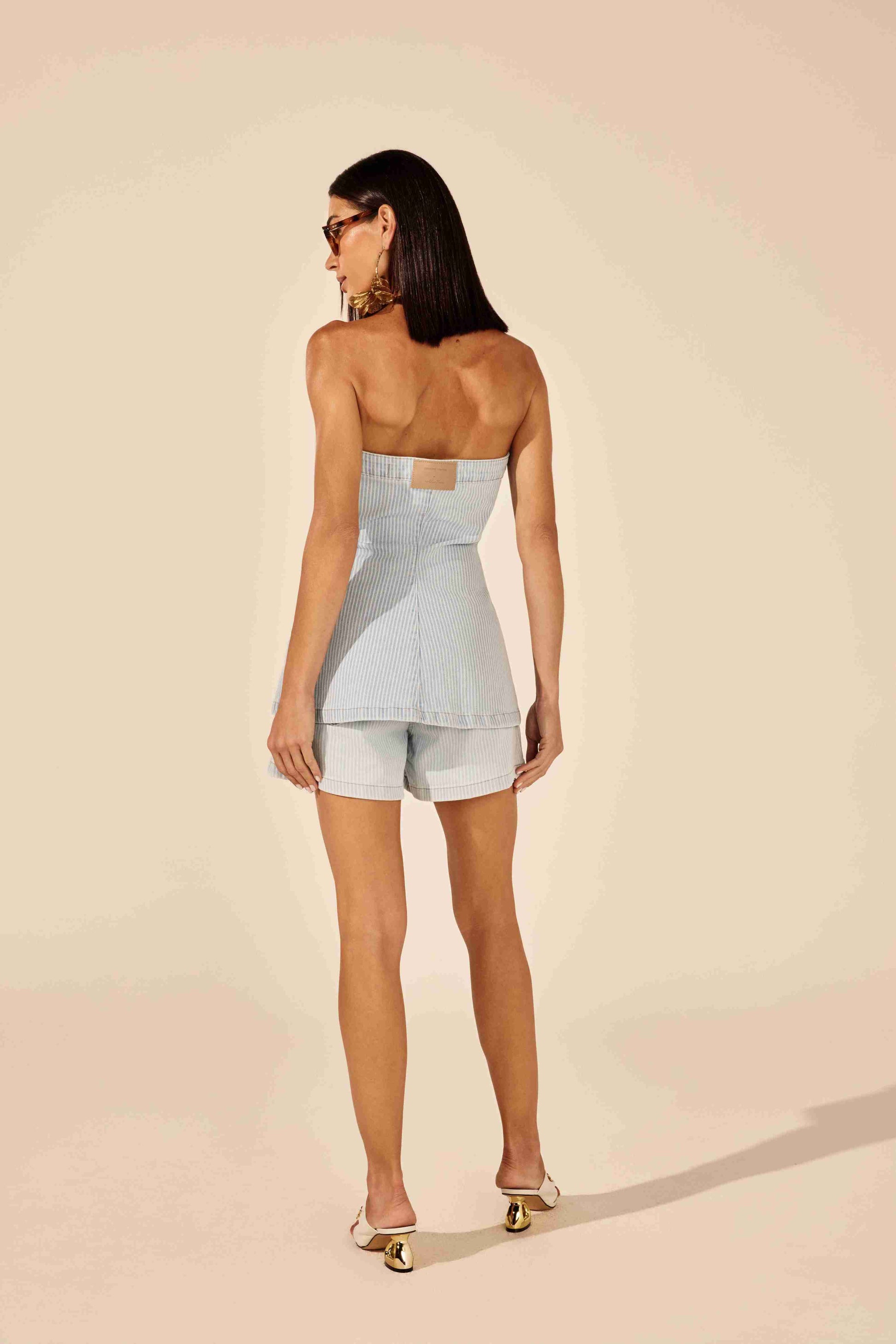 Blusa tomara que caia jeans azul listrada - modelo posando com ousadia em fundo urbano Onça Preta
