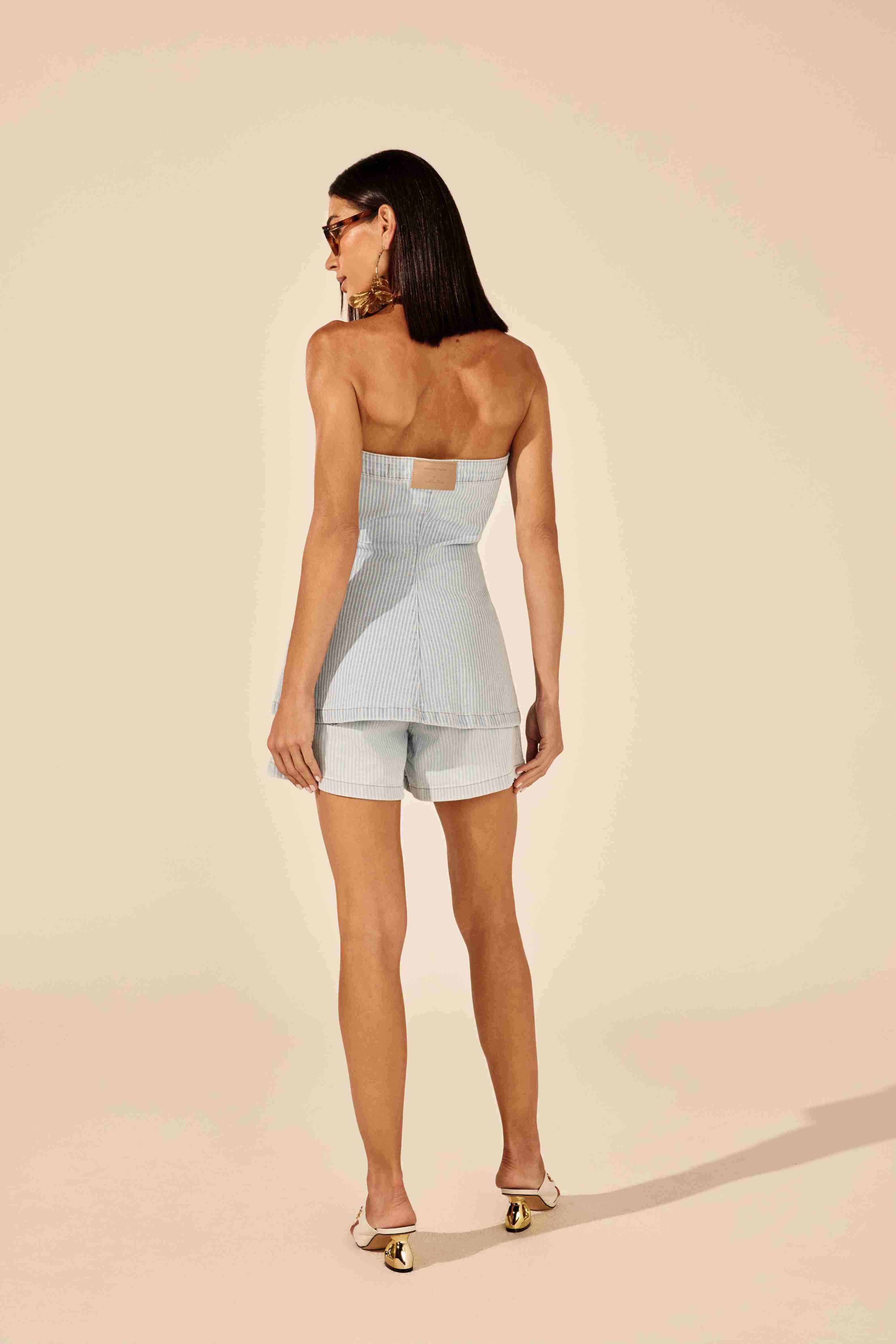 Blusa tomara que caia jeans azul listrada - modelo posando com ousadia em fundo urbano Onça Preta
