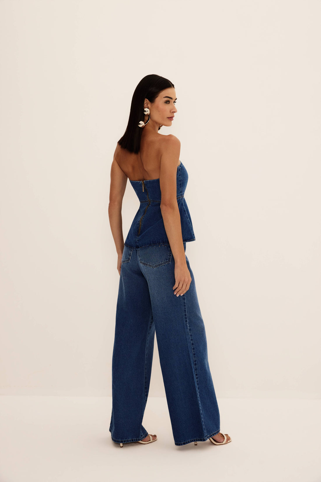 Blusa jeans tomara que caia azul com decote coração, recortes e barra peplum, vista de frente com cinto