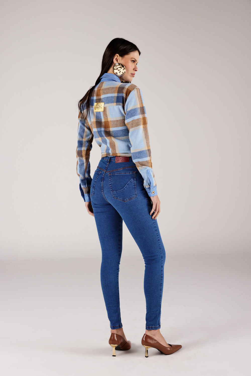  Calça super skinny jeans azul médio recorte no bolso, look de frente com flanela xadrez Onça Preta