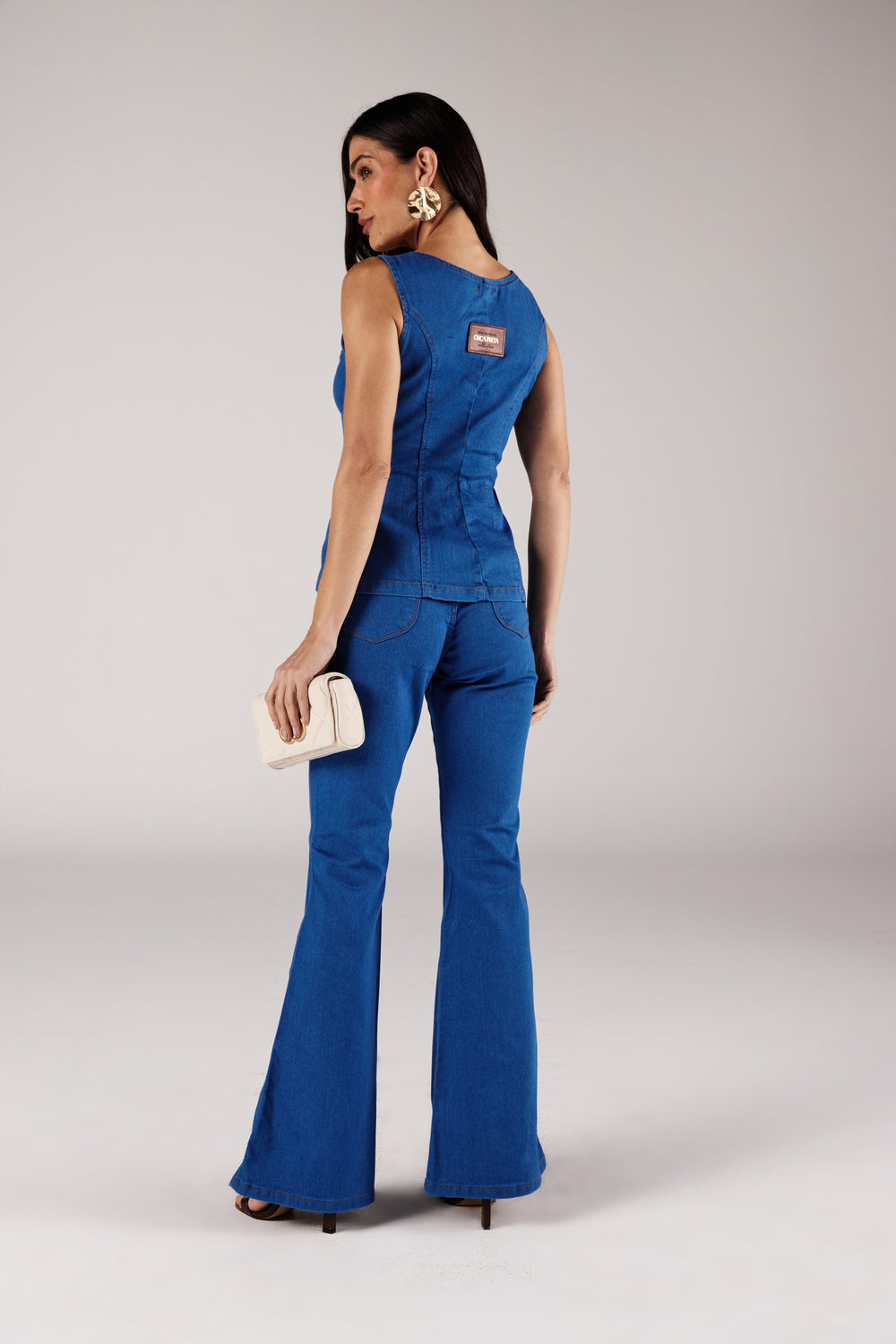 Calça flare jeans azul médio bolso arredondado, vista traseira com blusa zíper frontal Onça Preta