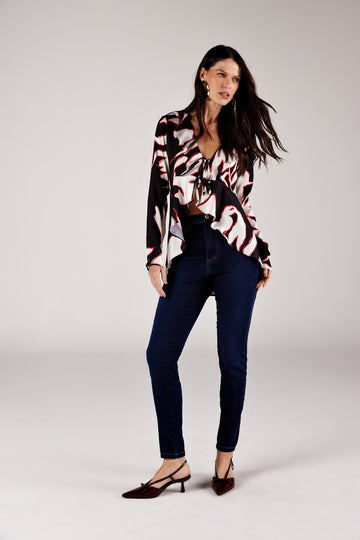 Calça skinny jeans azul escuro cintura alta, look de frente com blusa estampada Onça Preta