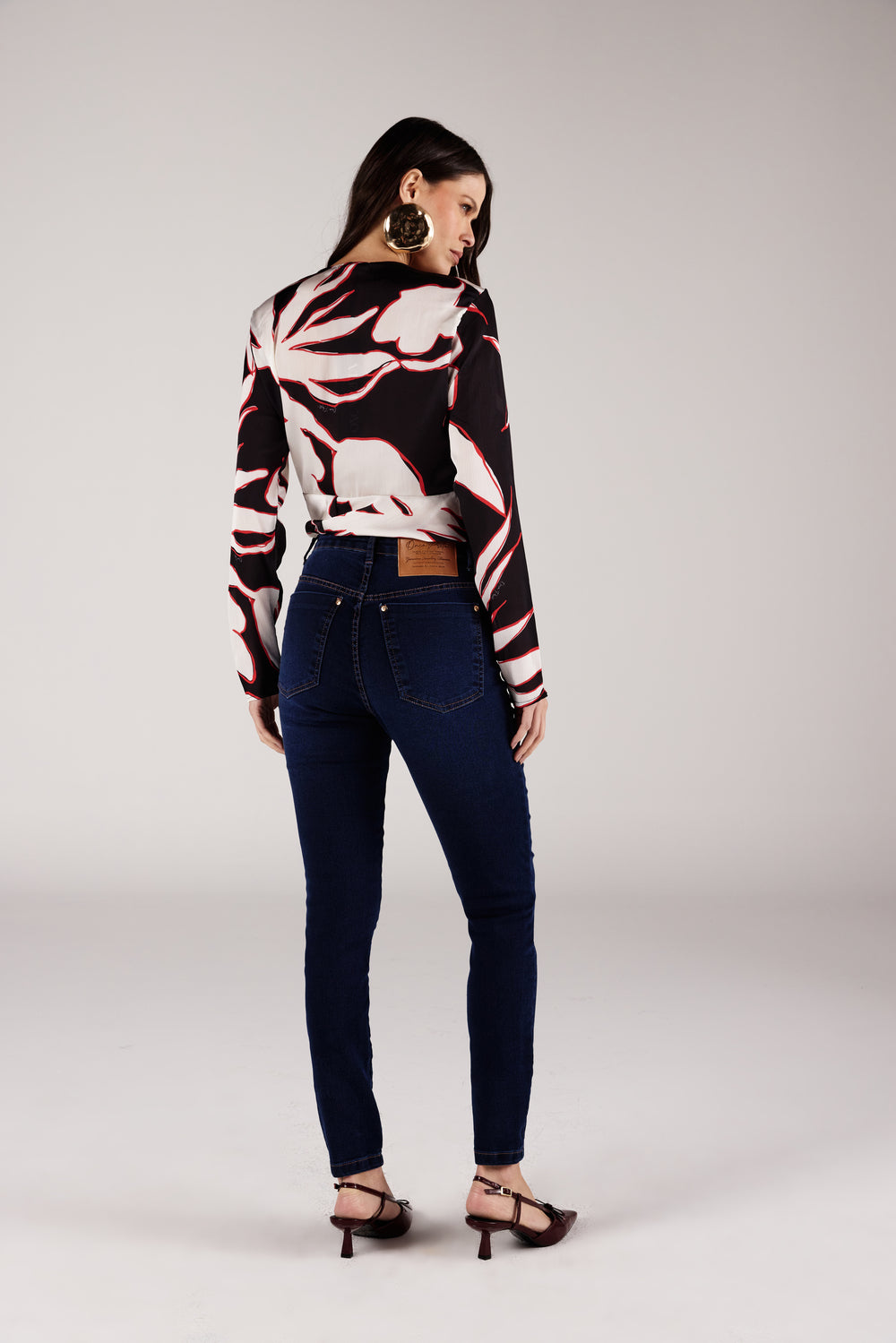 Calça skinny jeans azul escuro cintura alta, look de frente com blusa estampada Onça Preta