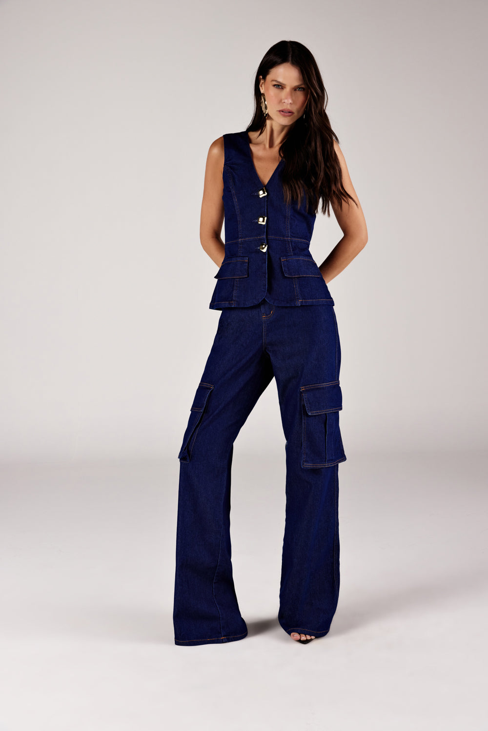 Calça reta jeans bolsos cargo azul escuro, look de frente com colete jeans Onça Preta