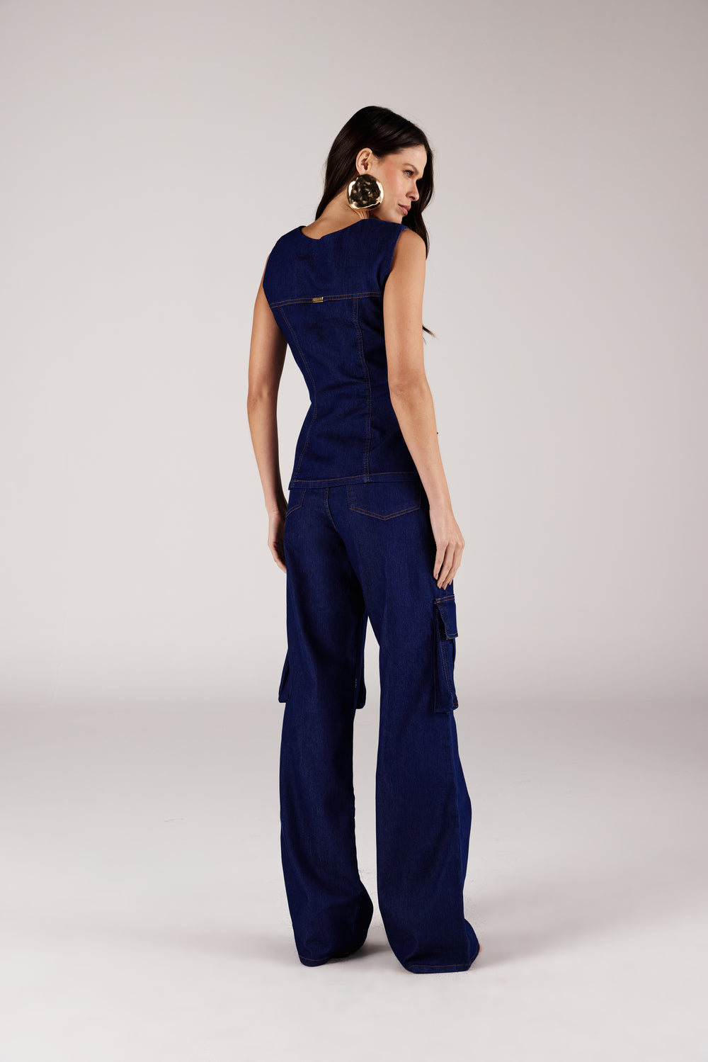 Calça reta jeans bolsos cargo azul escuro, vista traseira com colete jeans Onça Preta