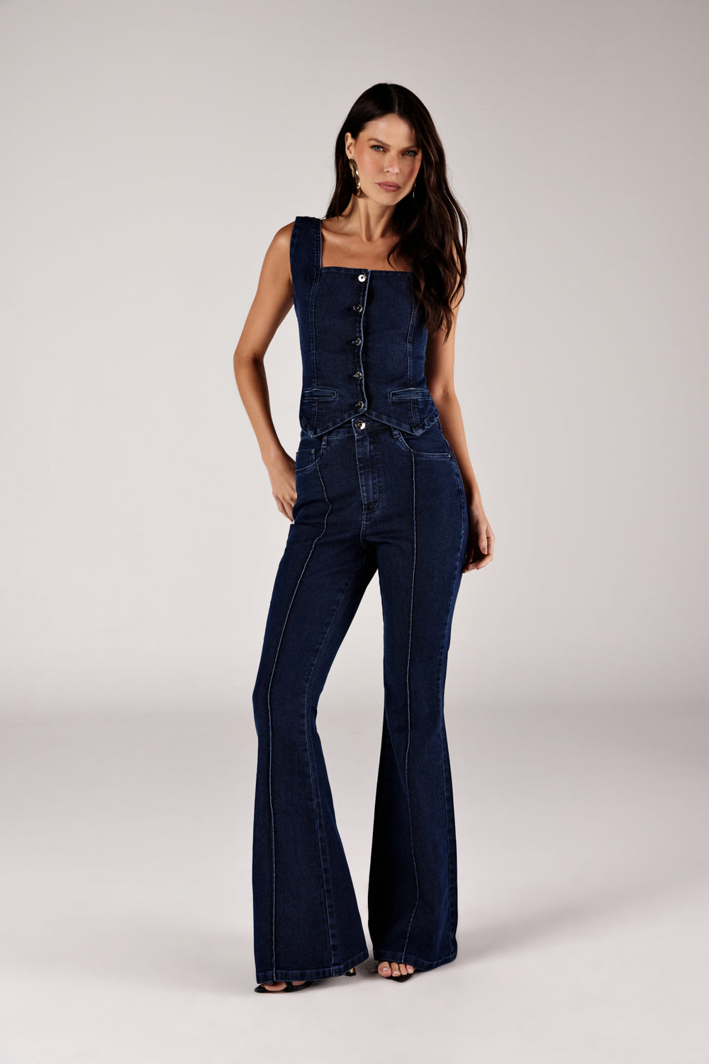 Calça flare jeans azul escuro frizo frontal, look de frente com colete jeans Onça Preta