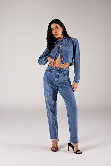 Calça mom jeans azul médio estampa paisley, look de frente com jaqueta cropped Onça Preta