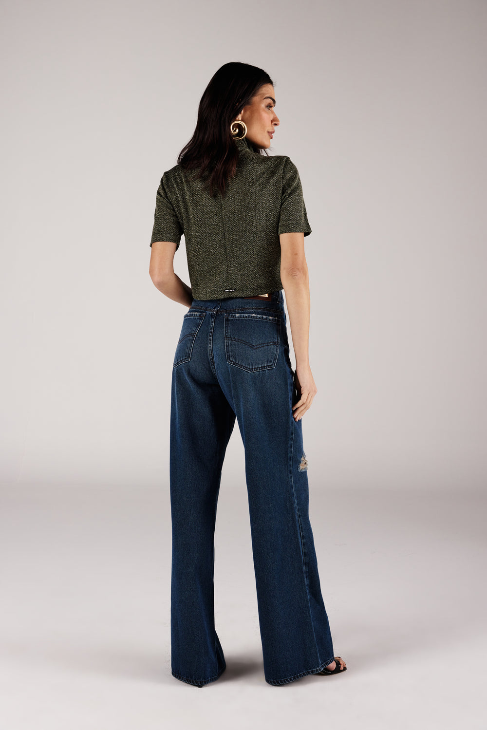 Calça wide leg jeans azul médio rasgada, vista traseira com blusa gola alta Onça Preta
