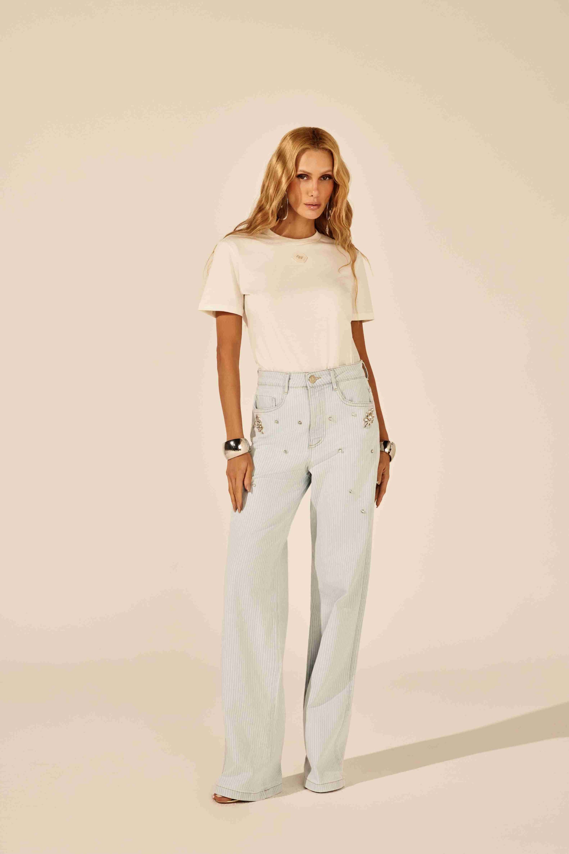 Calça reta listrada azul com pedraria - modelo em pose elegante, transmitindo confiança Onça Preta
