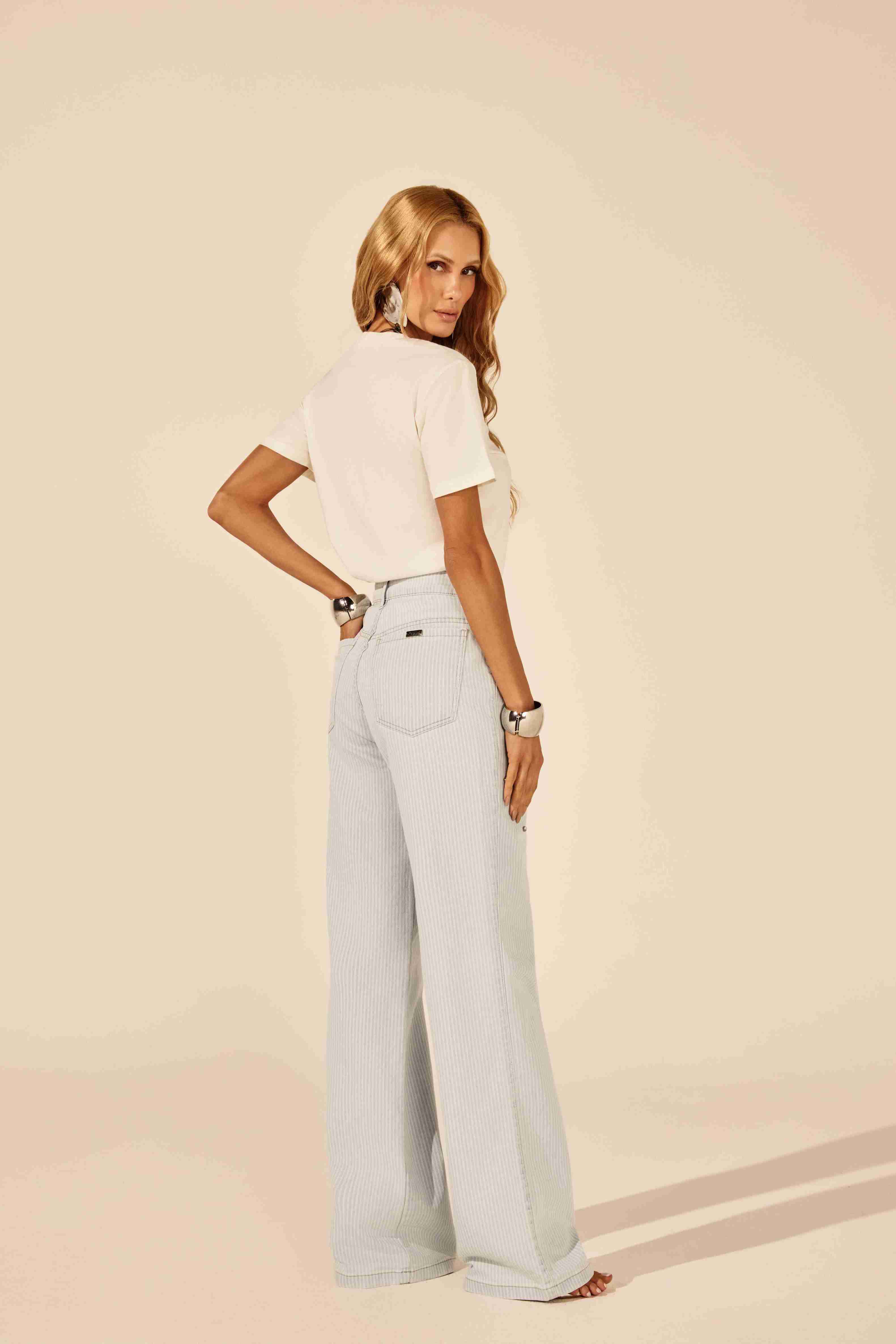 Calça reta listrada azul com pedraria - modelo em pose elegante, transmitindo confiança Onça Preta

