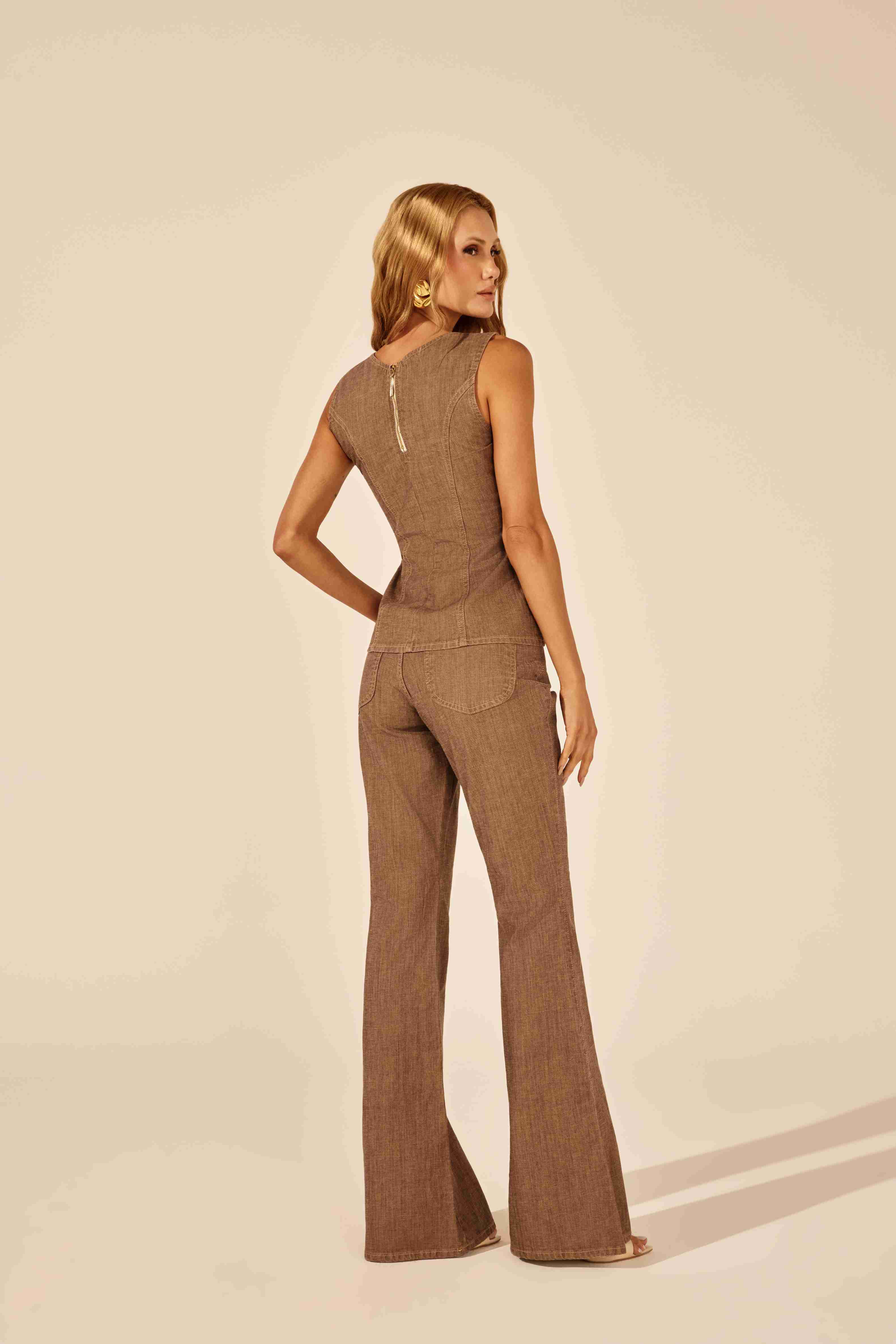 Calça flare amaciada marrom - modelo posando elegante com a peça em estúdio Onça Preta
