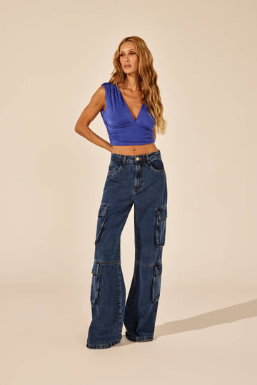 Calça jeans reta cargo com bolsos em fole, look de frente com top azul Onça Preta
