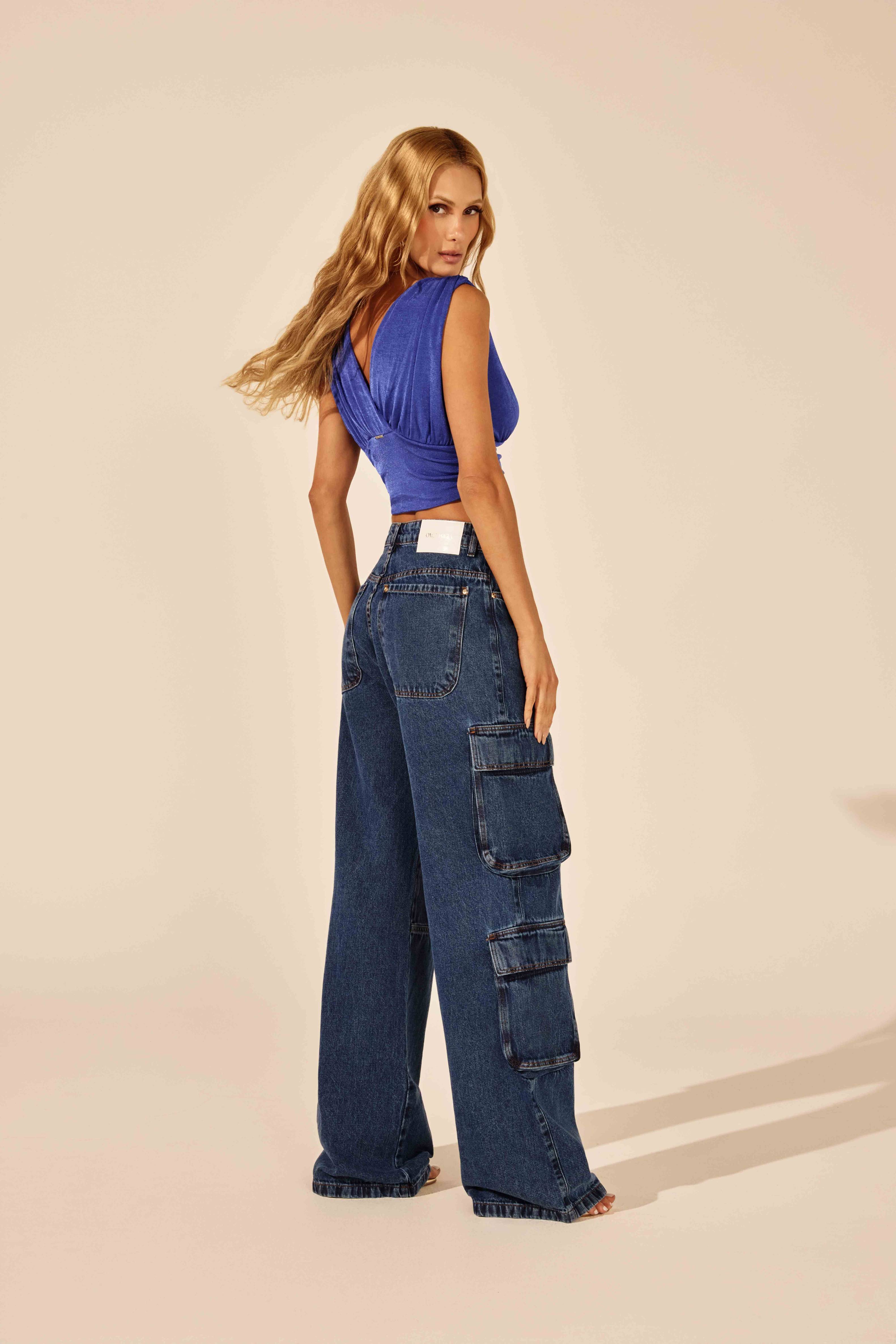 Calça jeans reta cargo com bolsos traseiros, vista traseira com top azul Onça Preta