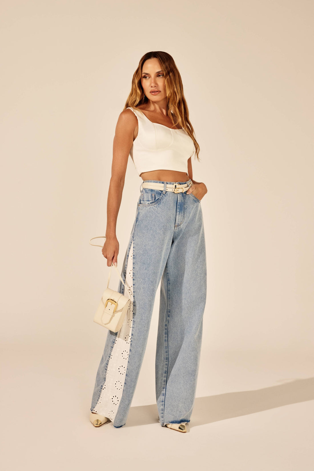 Calça jeans wideleg lavação clara com faixa em laise, look de frente com top corselet Onça Preta