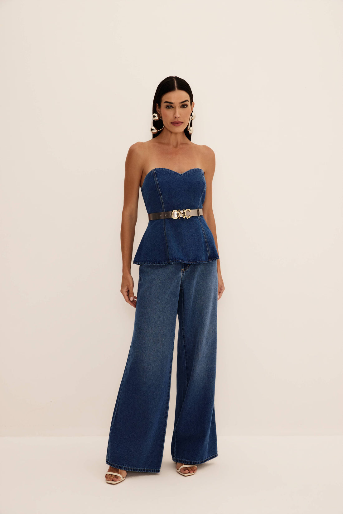 Calça jeans wide leg azul de lavagem média com perna ampla até o chão, vista de frente