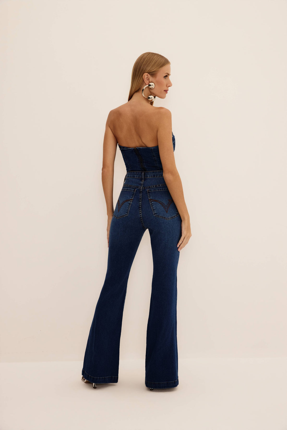 Calça jeans flare azul de cintura alta e lavagem escura, vista de frente com cinto