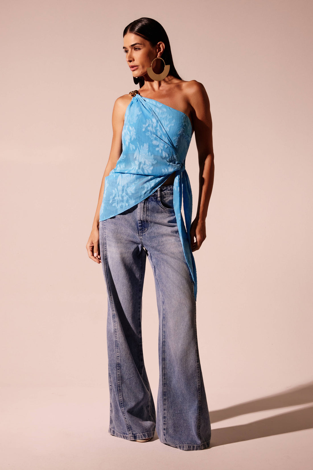 alça wide leg jeans azul clara com recorte lateral, look frontal com blusa ombro único azul Onça Preta