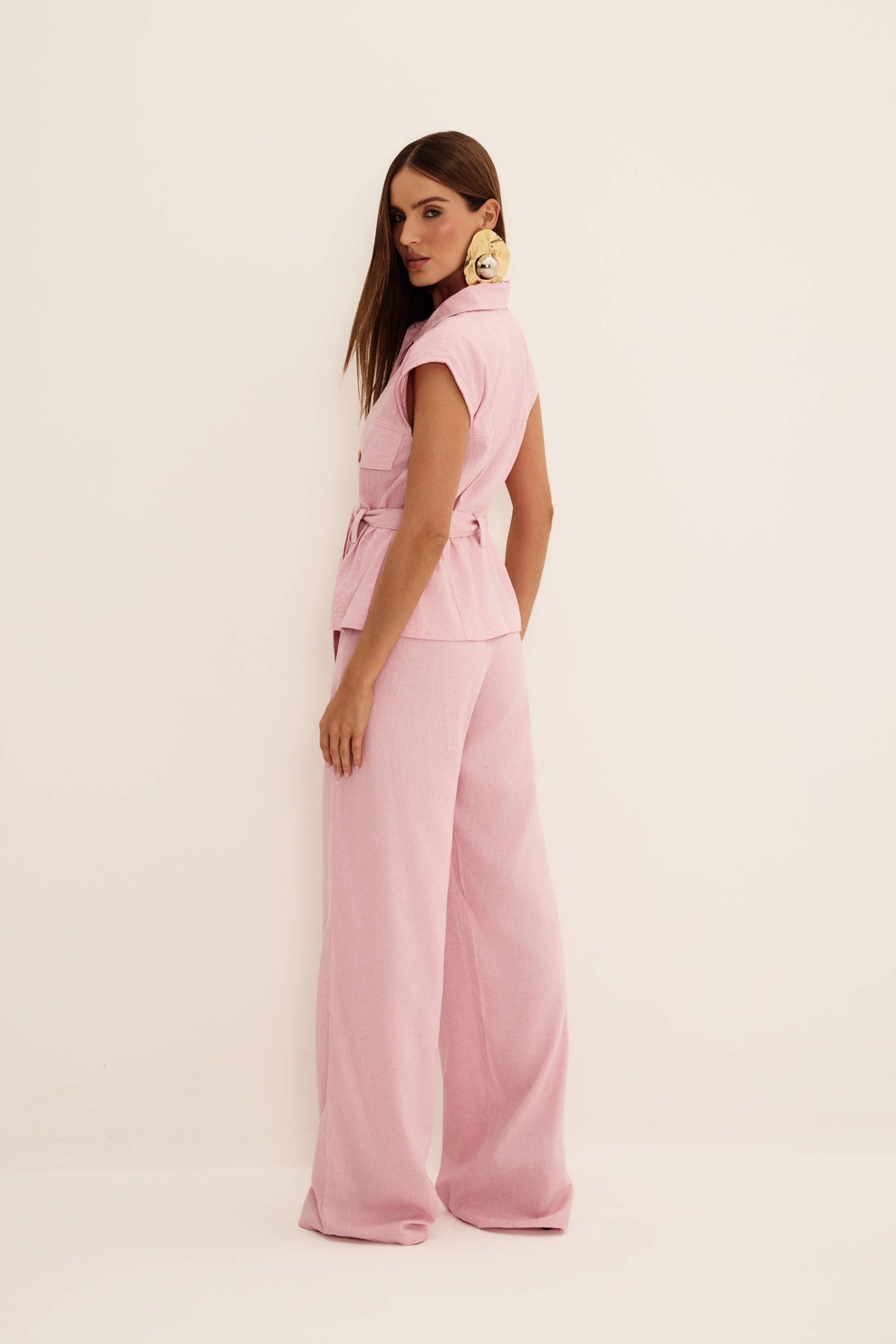 Colete com cinto jeans rosa visto de costas, com gola, cava ampla e faixa amarrada na cintura