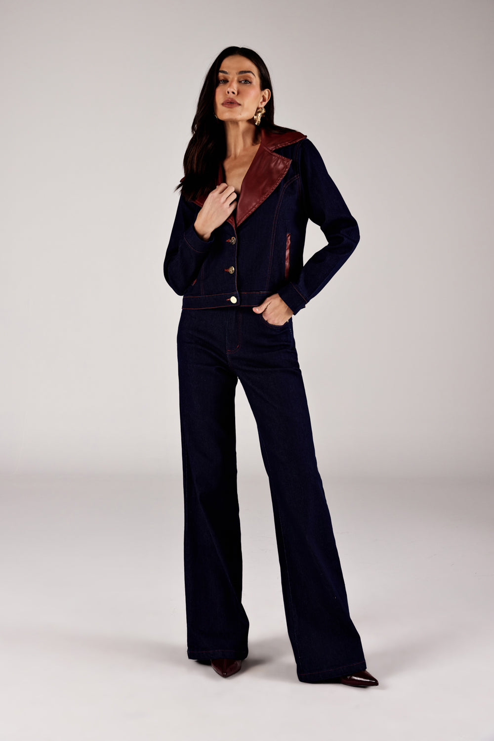 Jaqueta jeans azul escuro detalhe couro vinho, look de frente com calça wide leg Onça Preta
