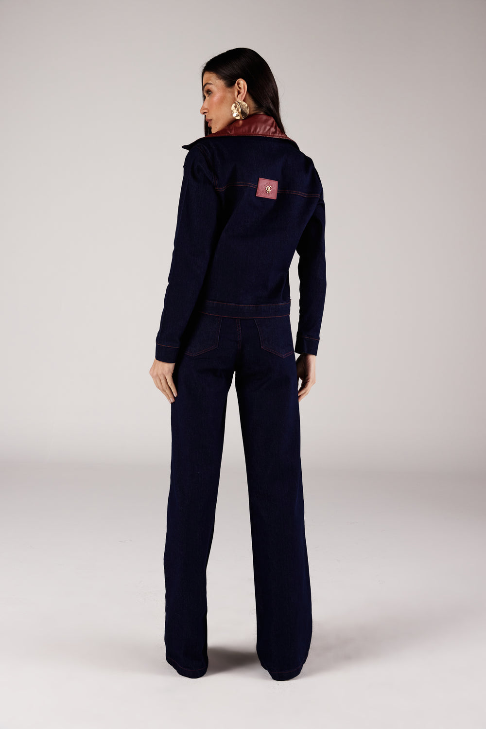 Jaqueta jeans azul escuro detalhe couro vinho, vista traseira com calça wide leg Onça Preta