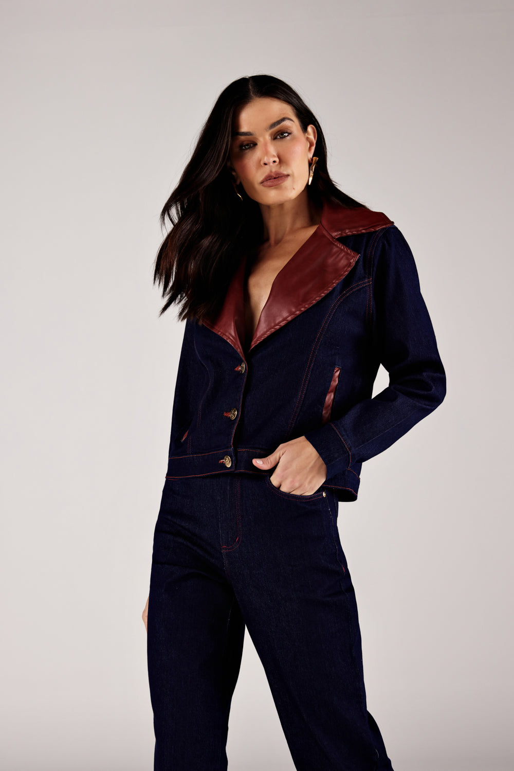 Jaqueta jeans azul escuro detalhe couro vinho, close do look de frente Onça Preta