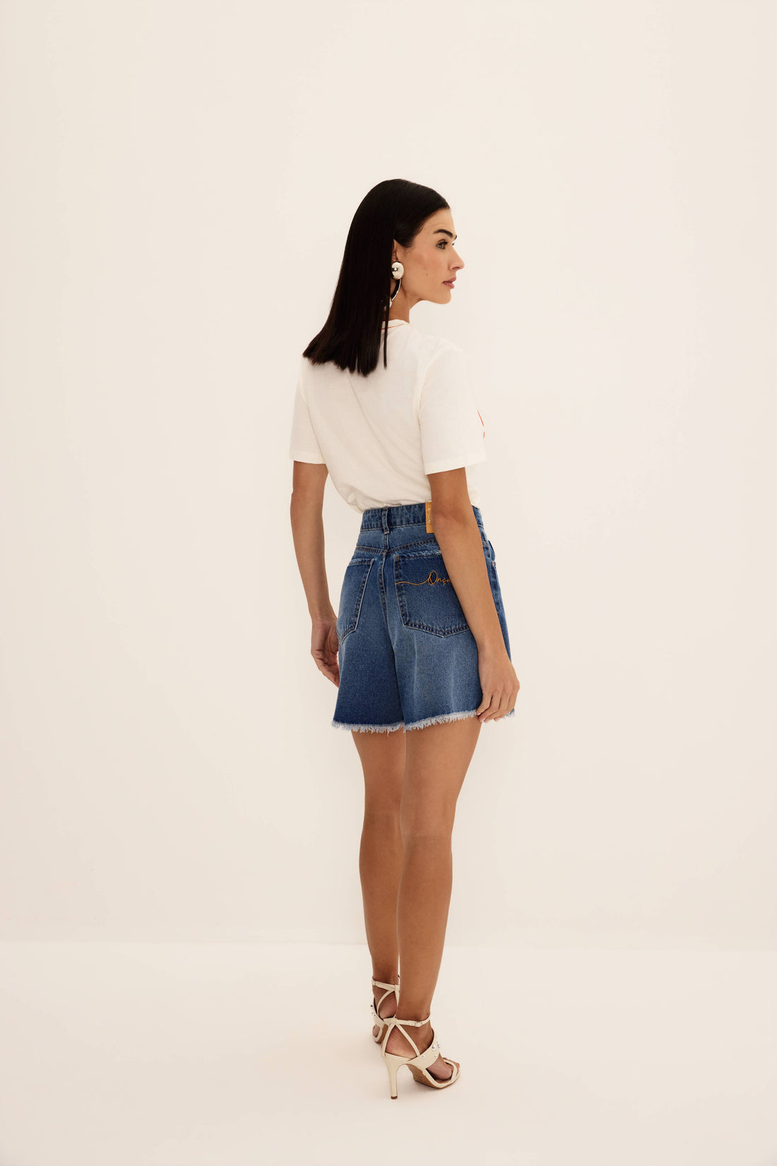 Shorts jeans azul de cintura alta com barra desfiada e perna ampla, vista de frente com cinto