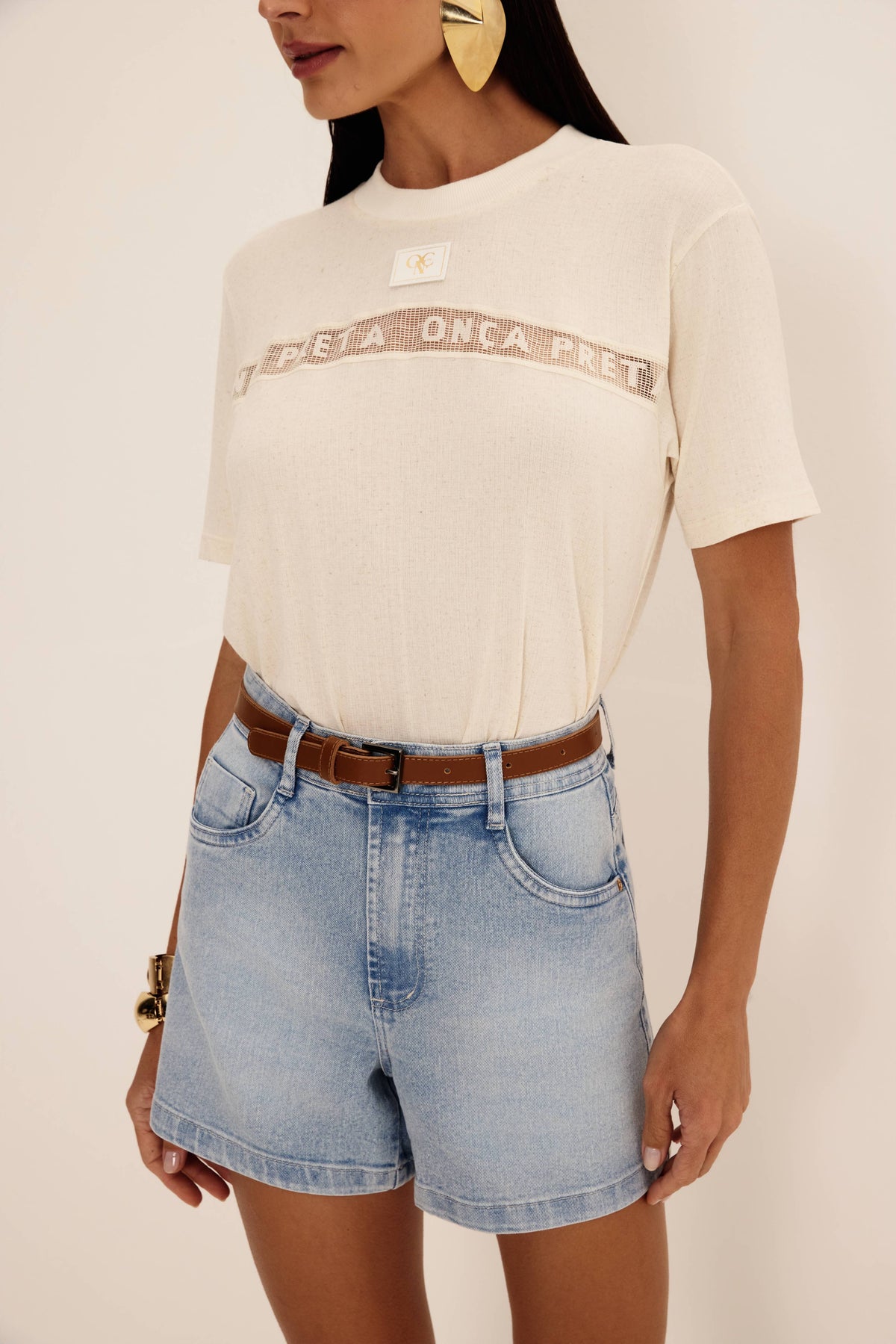 Shorts jeans claro visto de frente, com cintura alta, cinco bolsos e lavação clara, com t-shirt