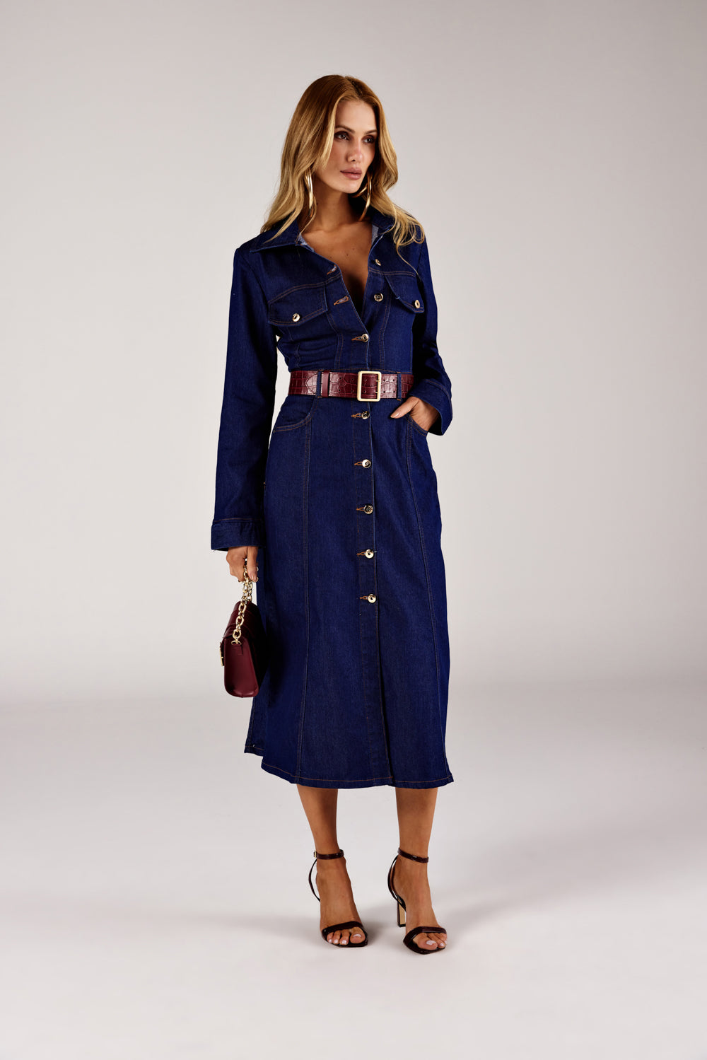 Vestido midi jeans abertura frontal azul escuro, look de frente com cinto vinho Onça Preta