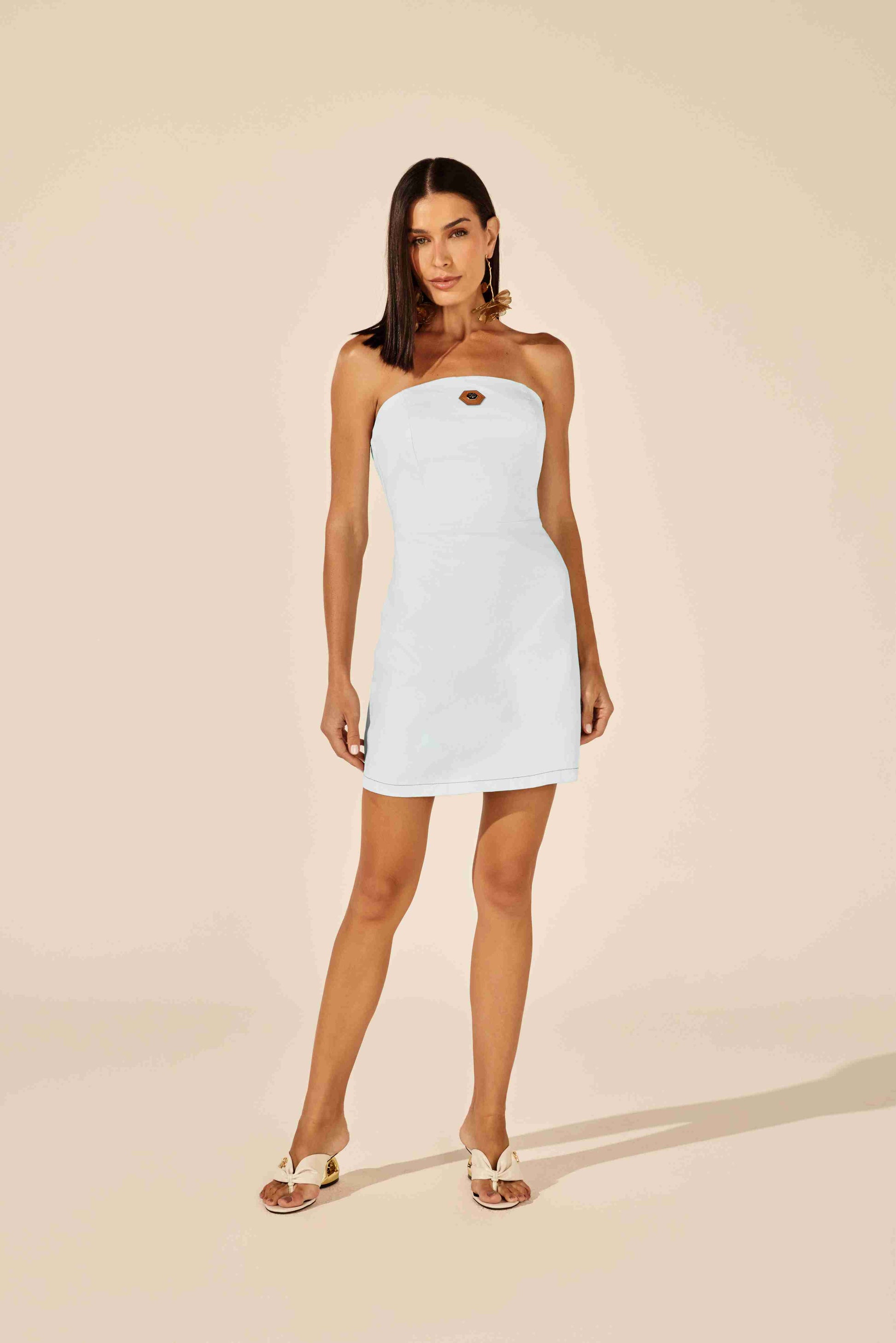Vestido curto jeans tomara que caia branco com detalhe dourado no busto em look de verão com sandálias Onça Preta