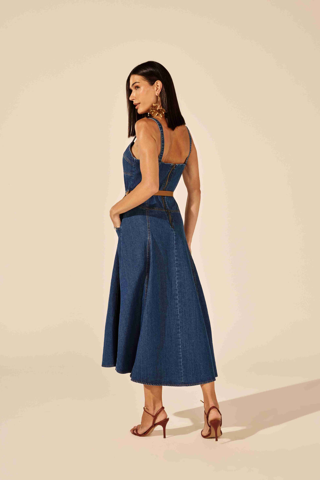 Vestido midi evasê corselet jeans azul em modelo posando para a câmera, exalando confiança Onça Preta
