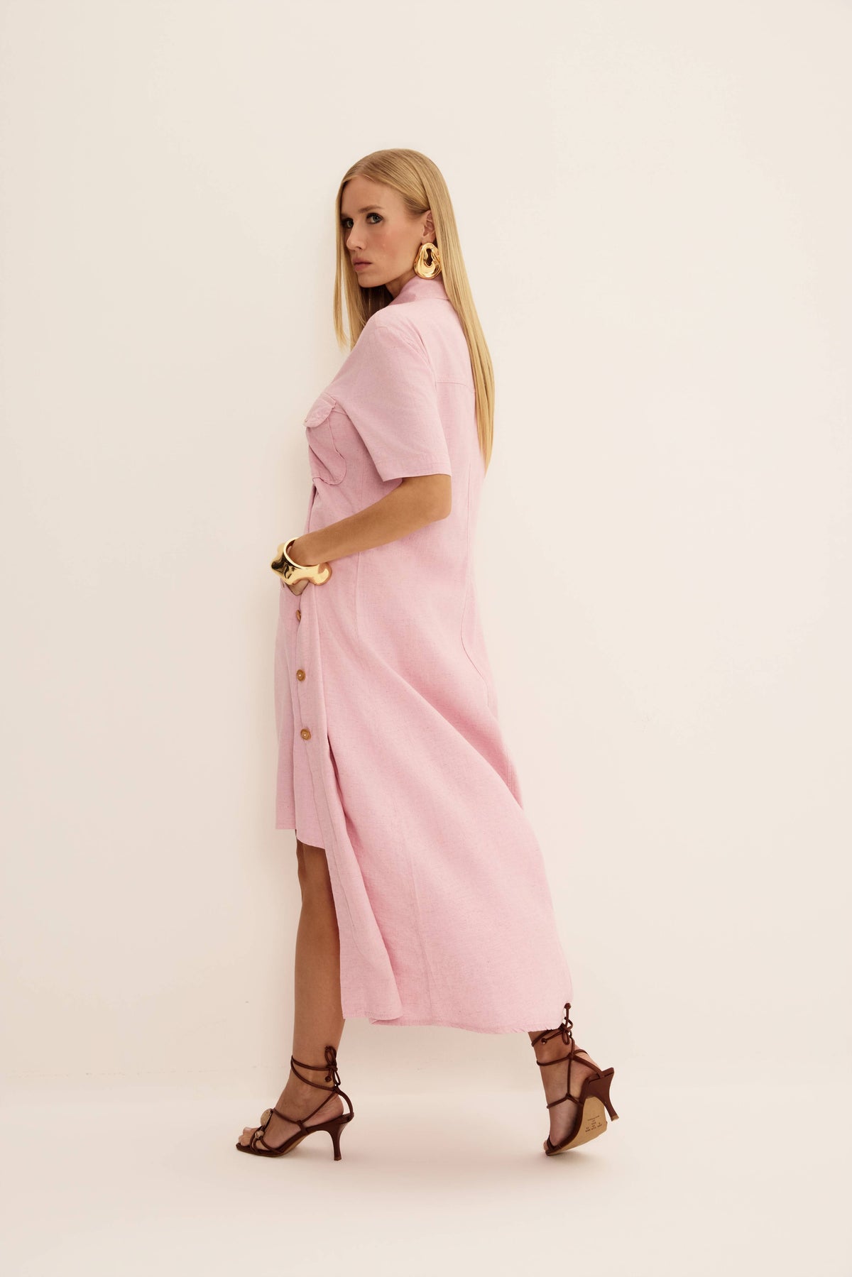 Vestido midi chemise jeans rosa em vista lateral com botões frontais, bolsos no peito e saia fluida
