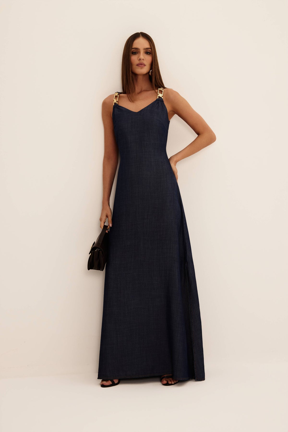 Vestido longo jeans azul escuro com alças de metal dourado e decote V, vista de frente