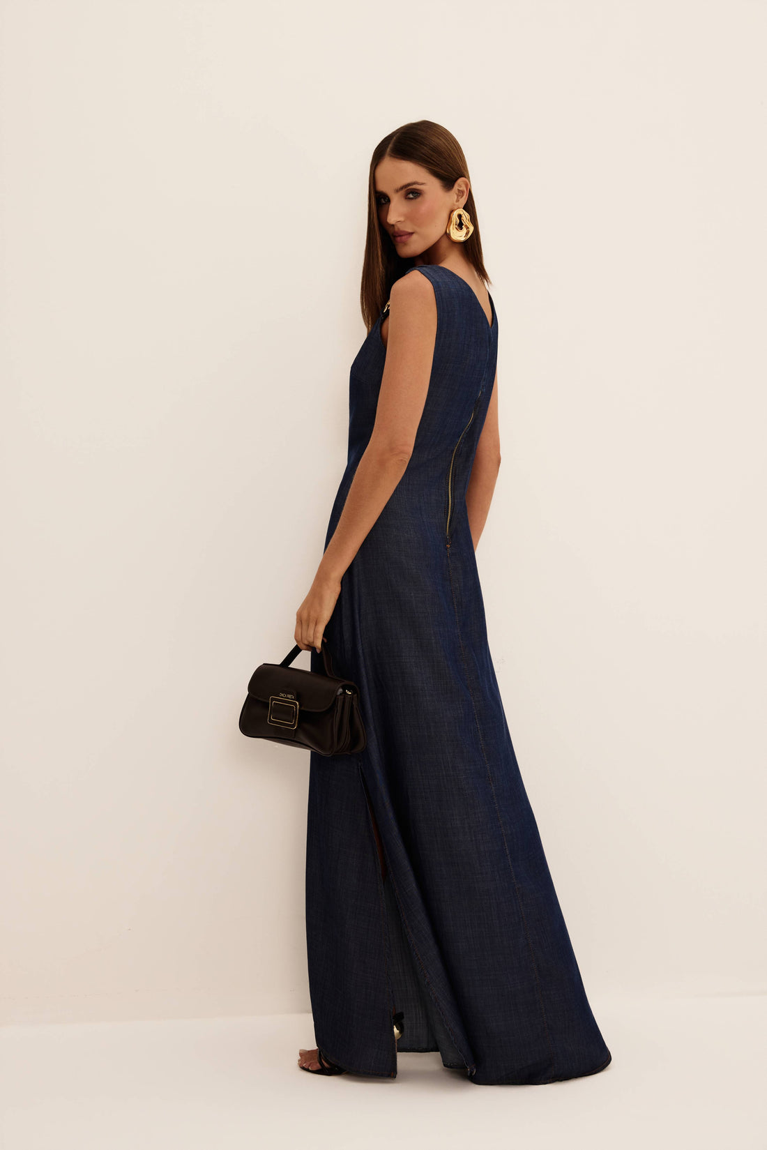 Vestido longo jeans azul escuro com alças de metal dourado e decote V, vista de frente