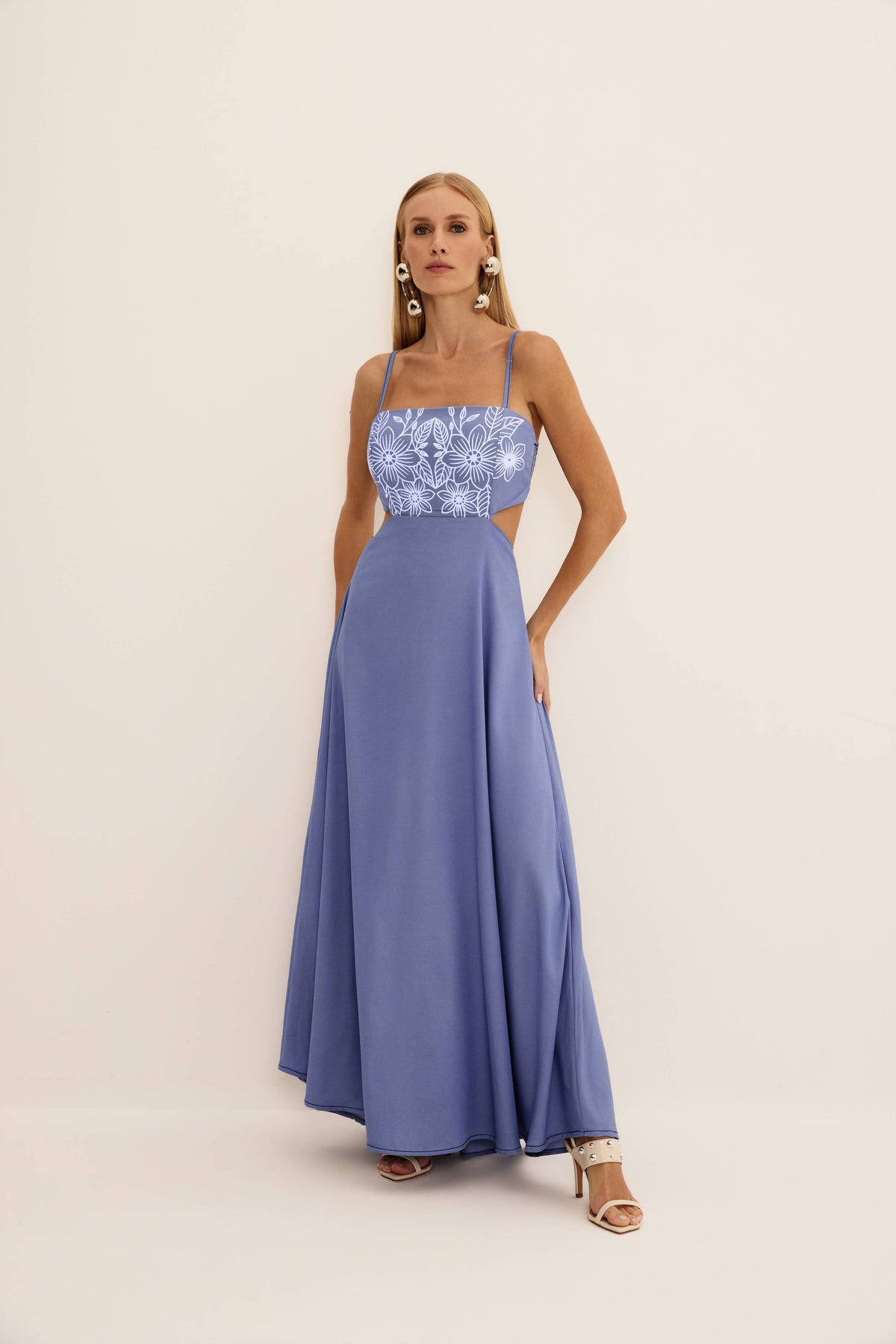 Vestido longo com aplicação puff jeans azul visto de frente, com flores em relevo no busto e saia ampla
