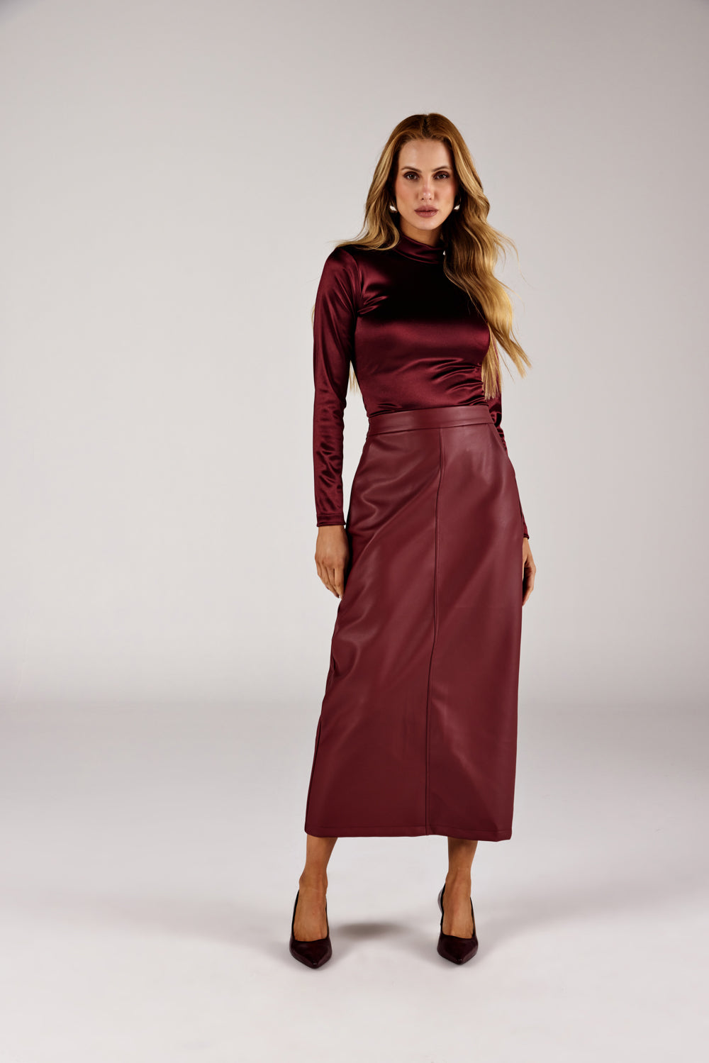 Body vinho gola alta cetim, look de frente com saia longa em couro Onça Preta