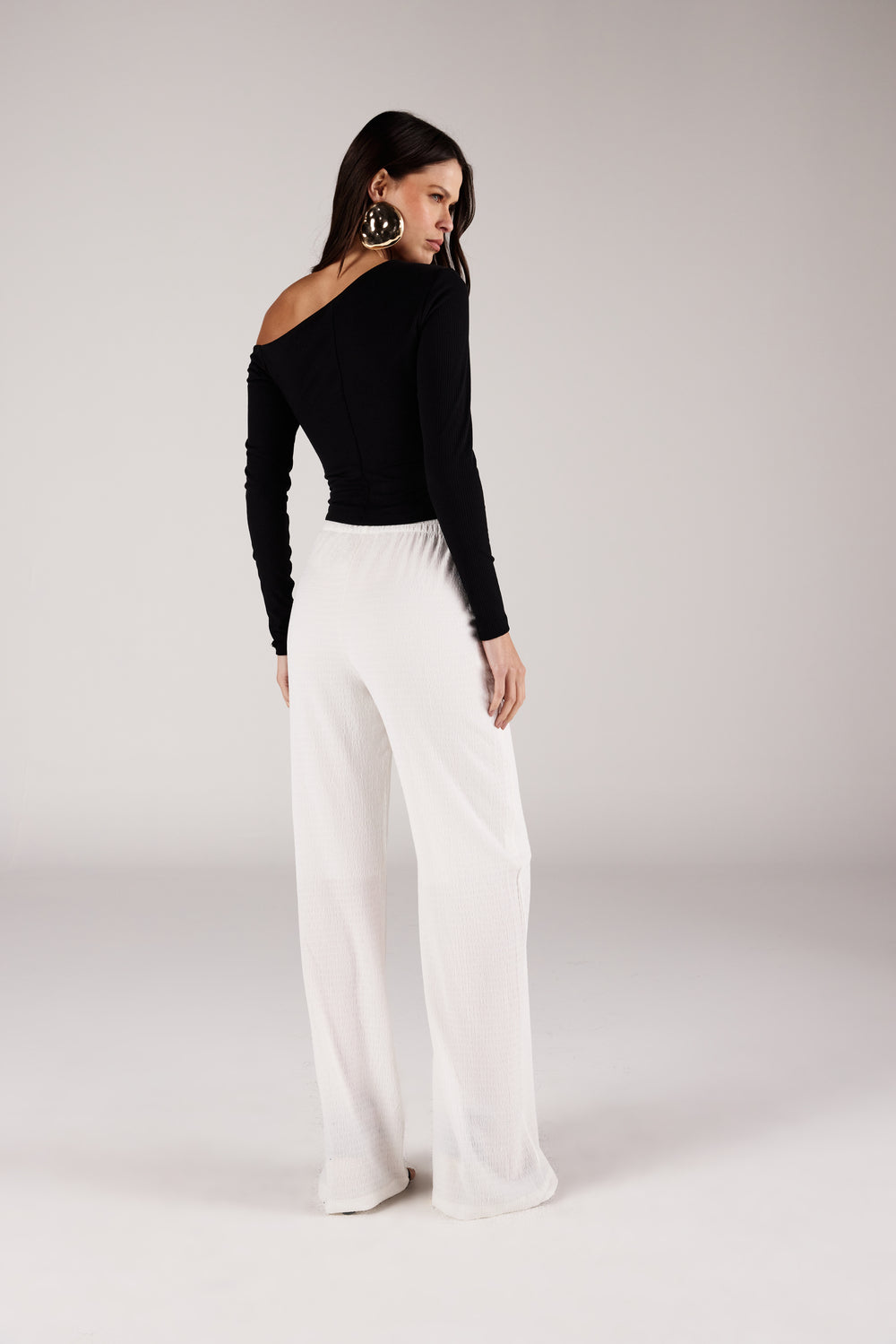 Blusa ombro caído assimétrica, vista traseira com calça texturizada Onça Preta