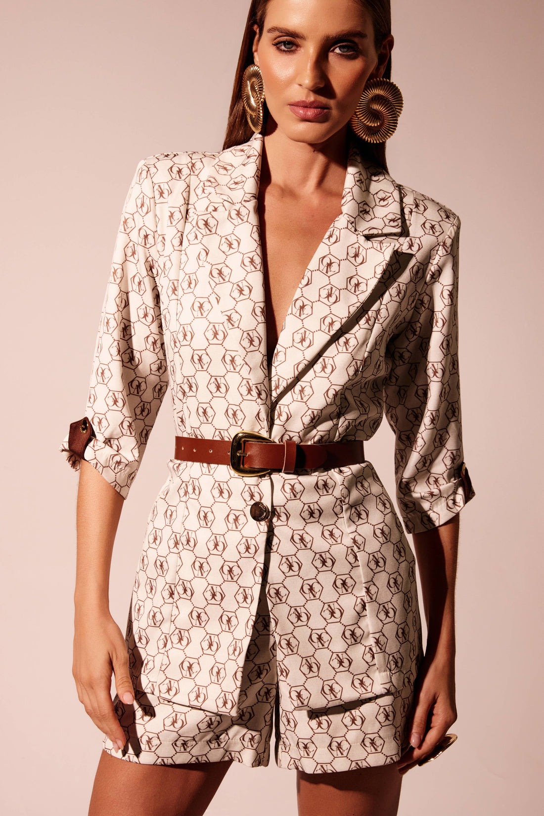 Blazer logomania marrom fundo cru com ombros estruturados e manga 3/4, look frontal com cinto Onça Preta