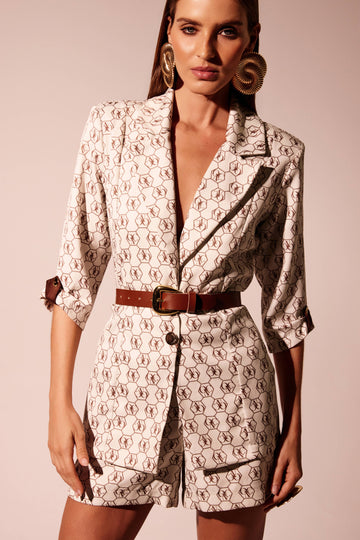 Blazer logomania marrom fundo cru com ombros estruturados e manga 3/4, look frontal com cinto Onça Preta