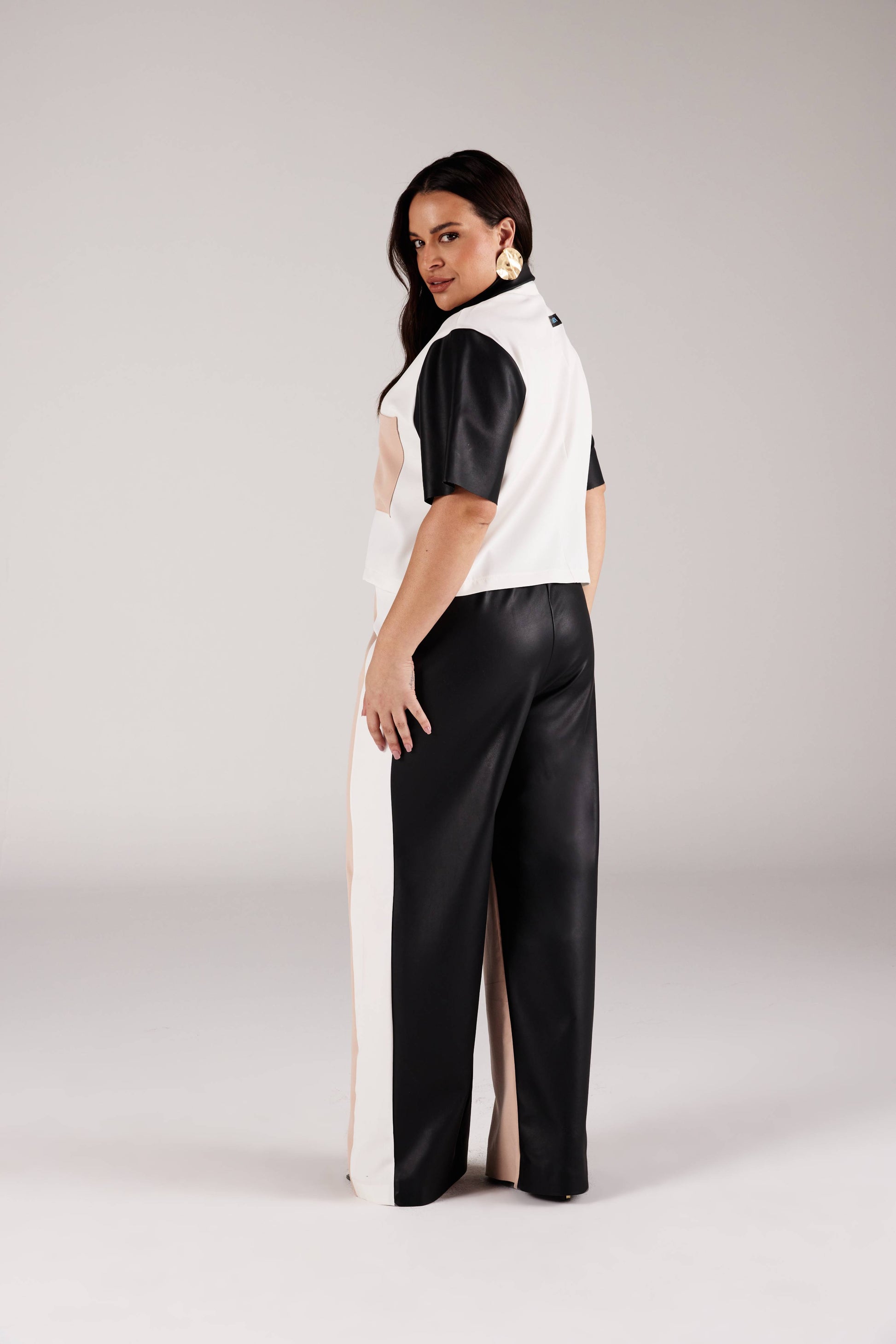 Calça reta color blocking vista de costas com painel preto acetinado e faixa off white lateral Curves Onça Preta