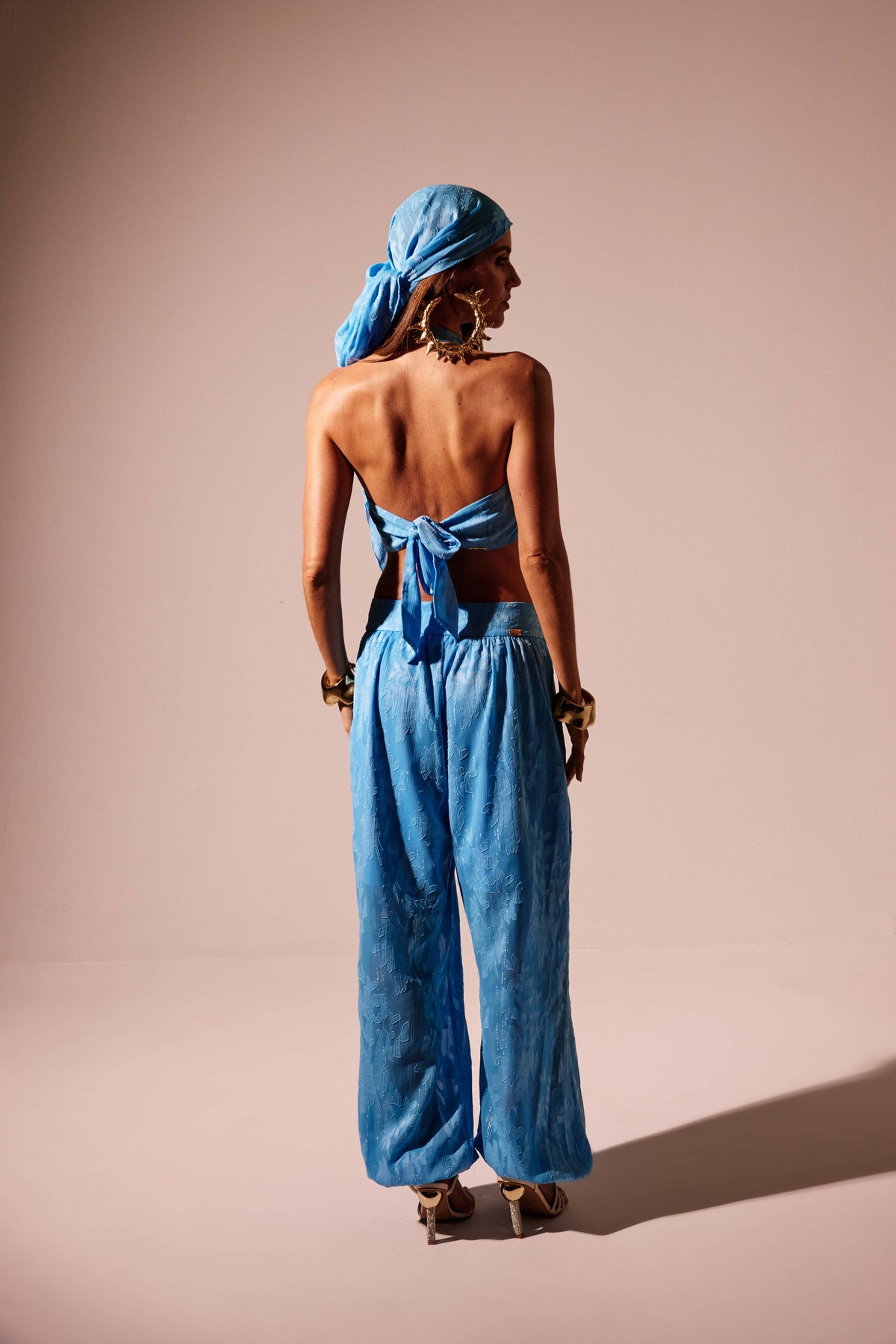 Calça aladim transparente azul, vista traseira com barra presa no tornozelo e top com amarração Onça Preta
