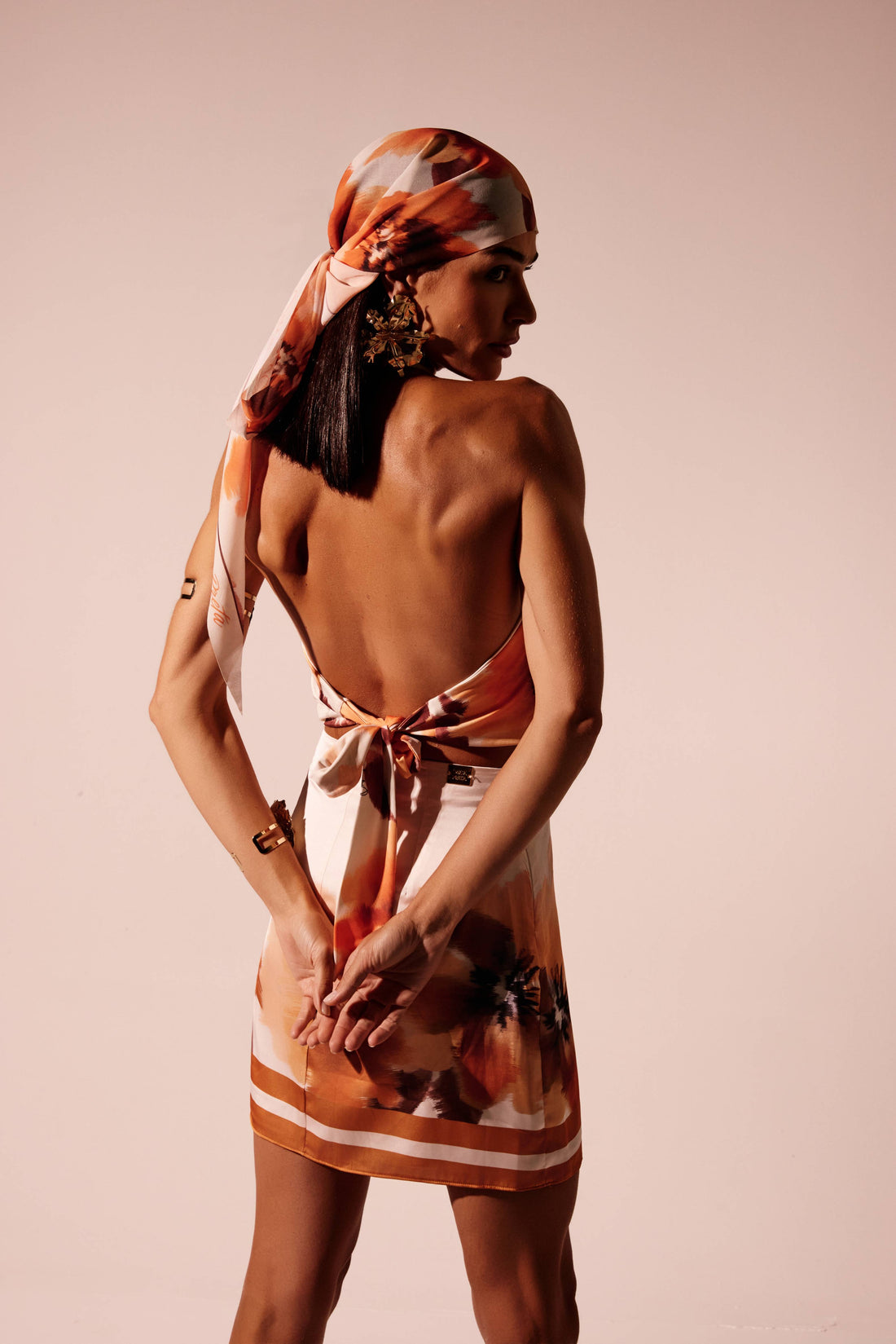 Saia curta floral laranja com estampa localizada, look frontal com blusa frente única da mesma estampa Onça Preta
