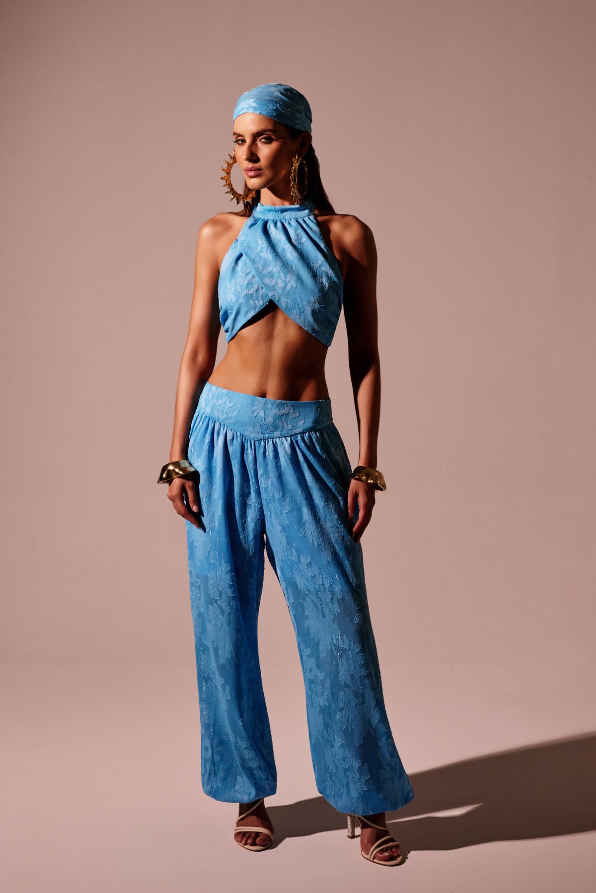 Top cropped frente única azul com transpasse e textura floral, look frontal com calça do mesmo tecido Onça Preta