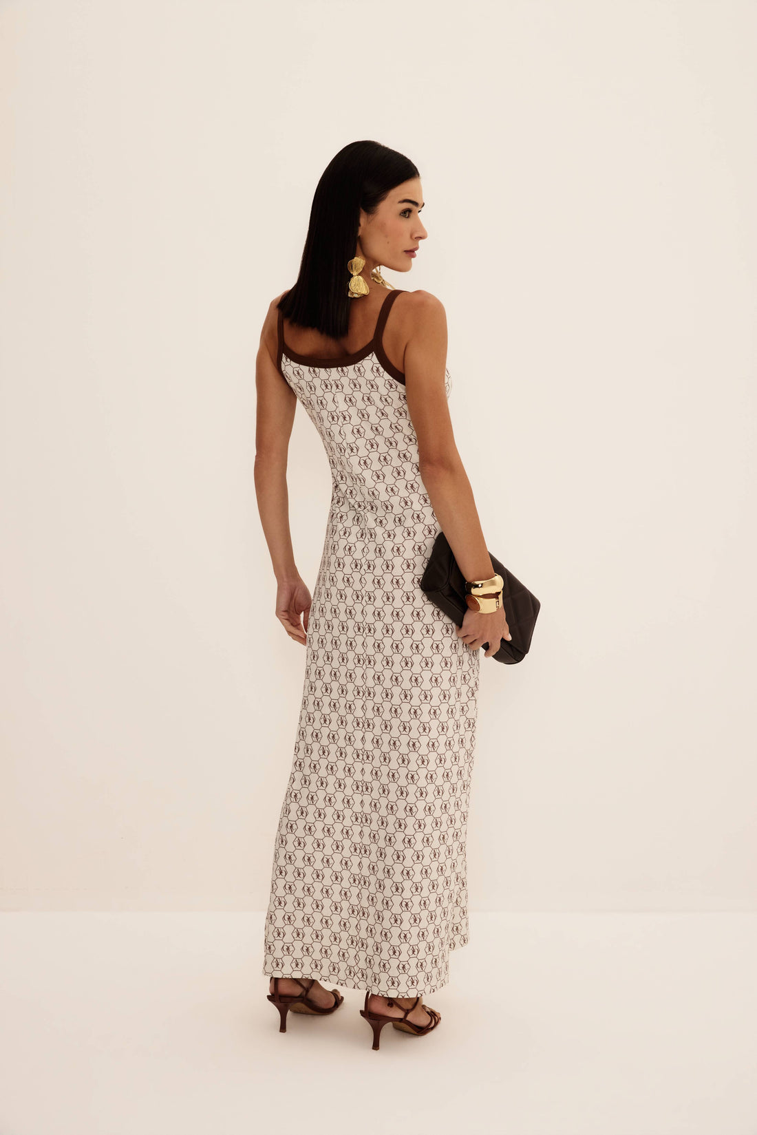 Vestido super midi regata logomania marrom fundo cru com viés em contraste e fenda lateral, look frontal com clutch preta Onça Preta
