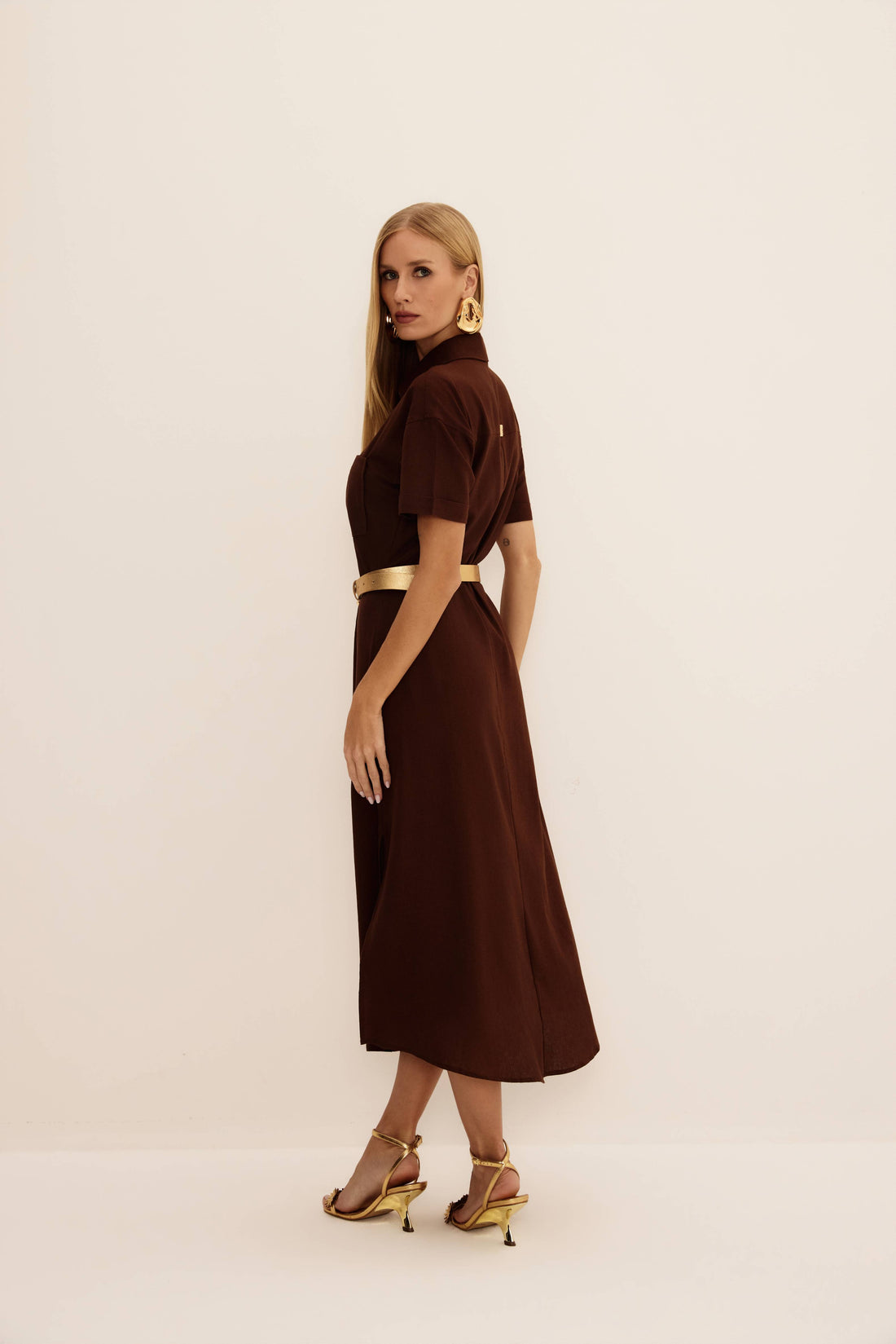 Vestido midi chemise marrom de linho com gola, botões dourados, bolsos no peito e cinto dourado, vista de frente